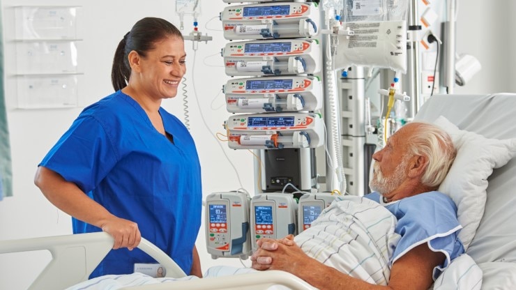 Krankenschwester lächelt Patienten an der eine Infusionstherapie erhält
