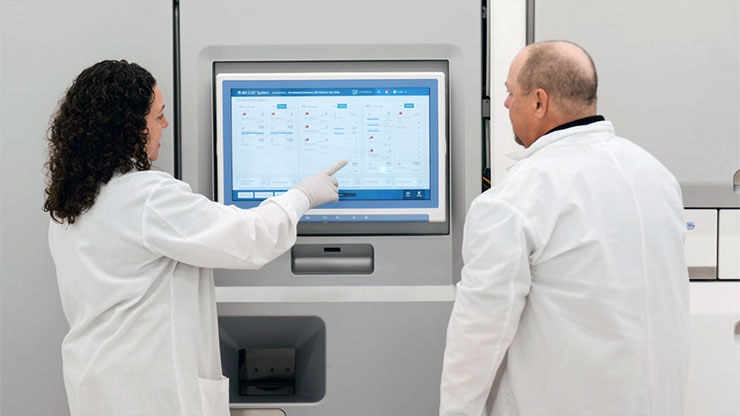 Lab technicians in white coats at a monitor of the BD COR™