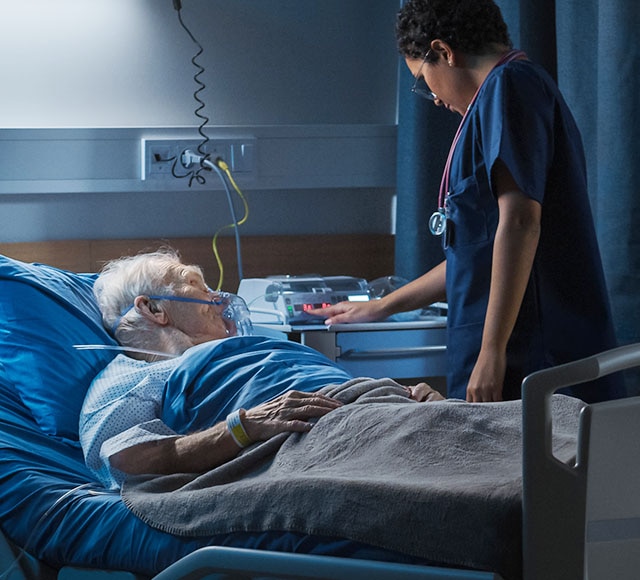 Lab worker sits at a computer surrounded by stacks of plated lab media.