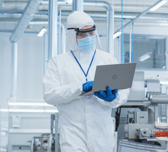 Scientist in cleanroom using laptop computer