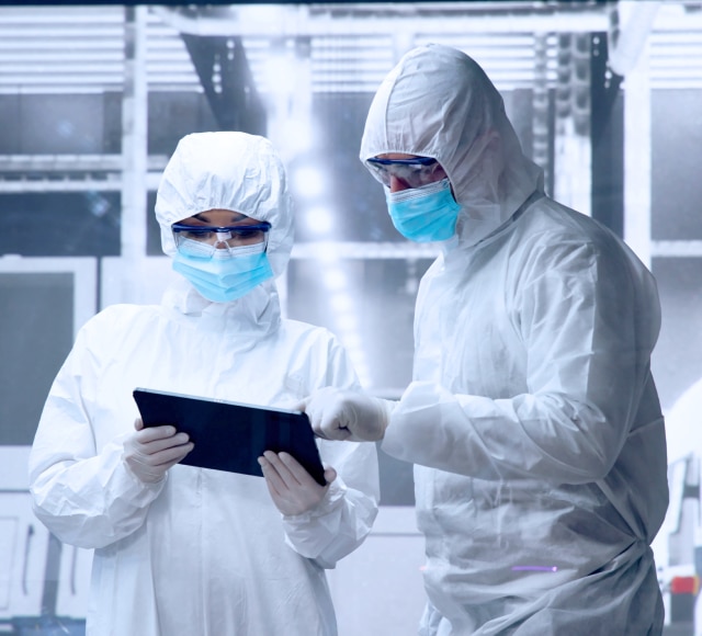 Scientists in protective suits using tablet