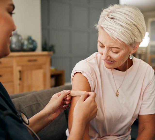 Healthcare worker applies bandage after vaccination at home