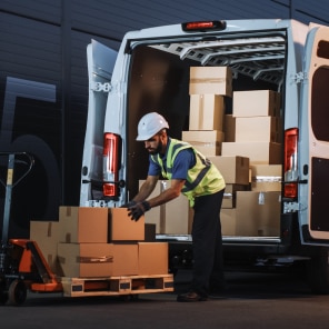 Worker unloading cardboard boxes from delivery van