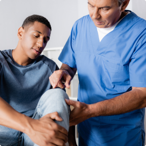 Doctor examining patient's knee in medical office