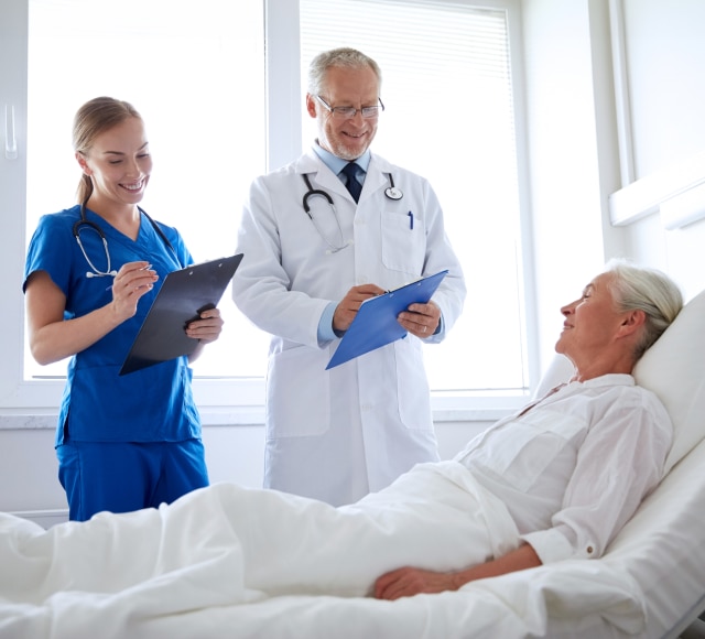 Doctors Consult With Patient in Hospital Room