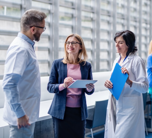 Medical professionals and businesswoman discussing in modern office