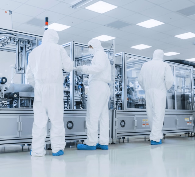 Scientists in cleanroom operating machinery