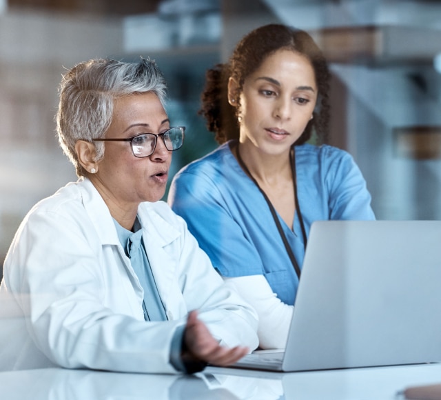 Medical professionals collaborating at laptop in clinic